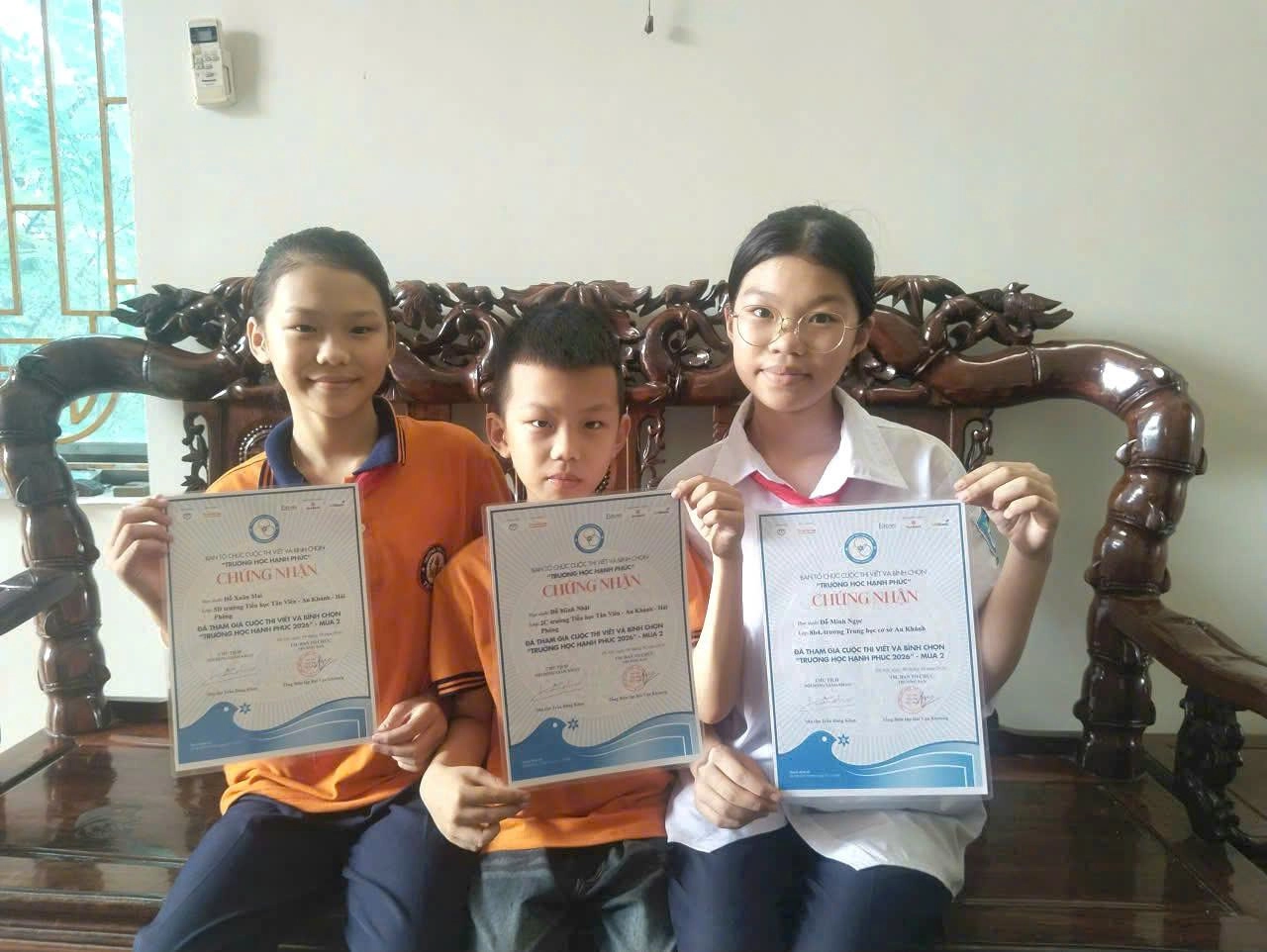 Ba chị em trong một gia đình hào hứng khoe giấy chứng nhận tham gia thi viết về “Trường học Hạnh phúc”